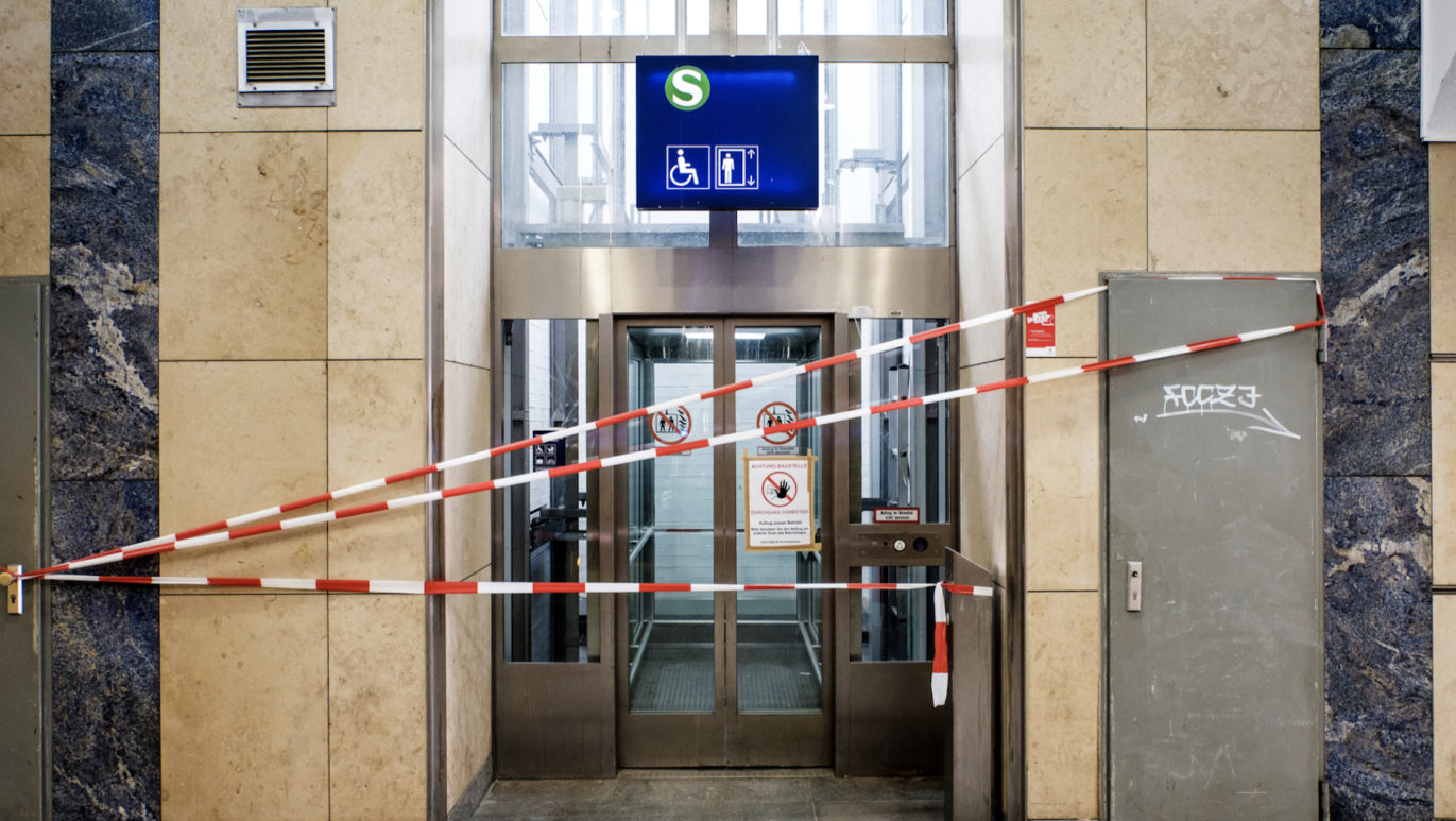 Red-white barrier tape blocks the entrance to a broken elevator. Seen at a German S-Bahn railway station. 