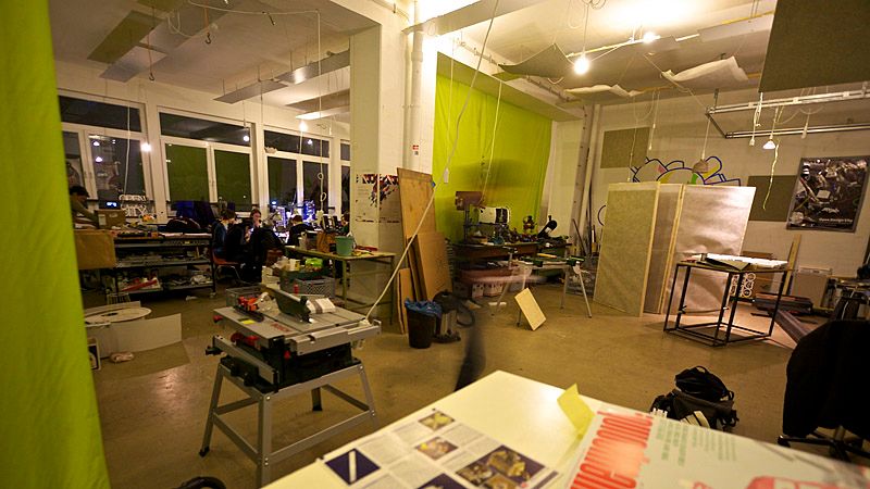 Photo of a stuffed workshop with various tools and a table saw in the front.